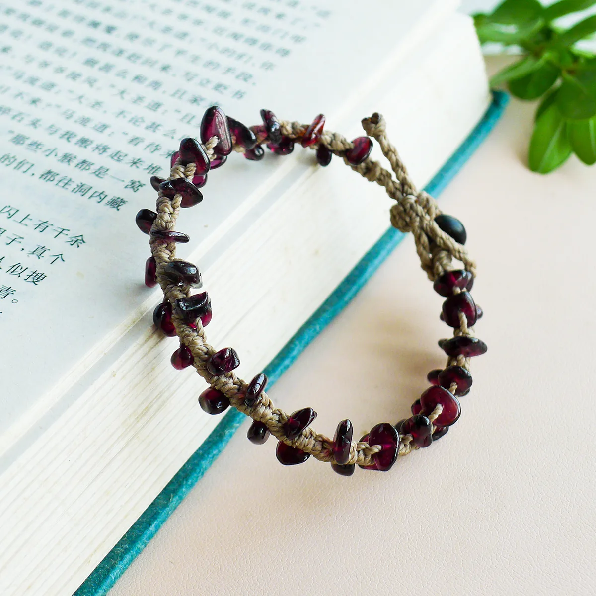 Handmade garnet chip bracelet styled beside an open book