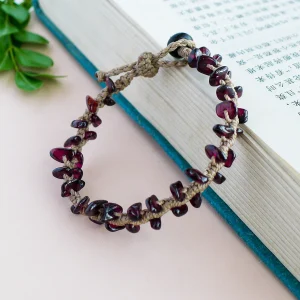 Adjustable garnet chip macrame bracelet with sliding closure styled on a book
