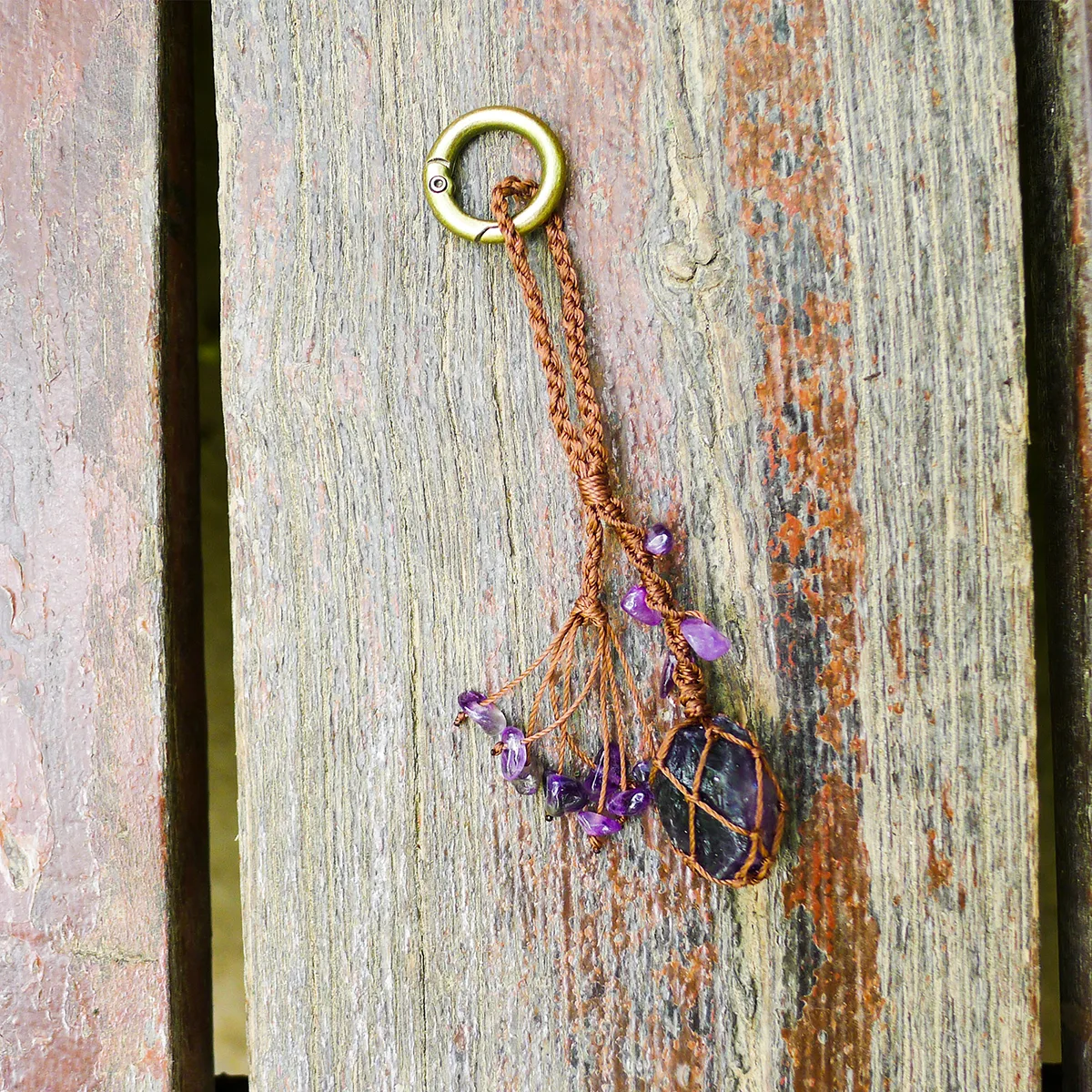 Violet Thread raw amethyst keychain laid flat on weathered grey wood texture. Natural rustic styling emphasizing natural gemstones aesthetic.