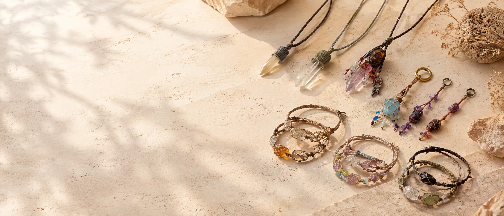 Handmade natural stone bracelets, necklaces, and charms arranged in warm sunlight